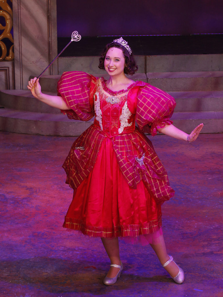 Theatre Shot of Cinderella wearing pretty red dress and waving a magic wand smiling